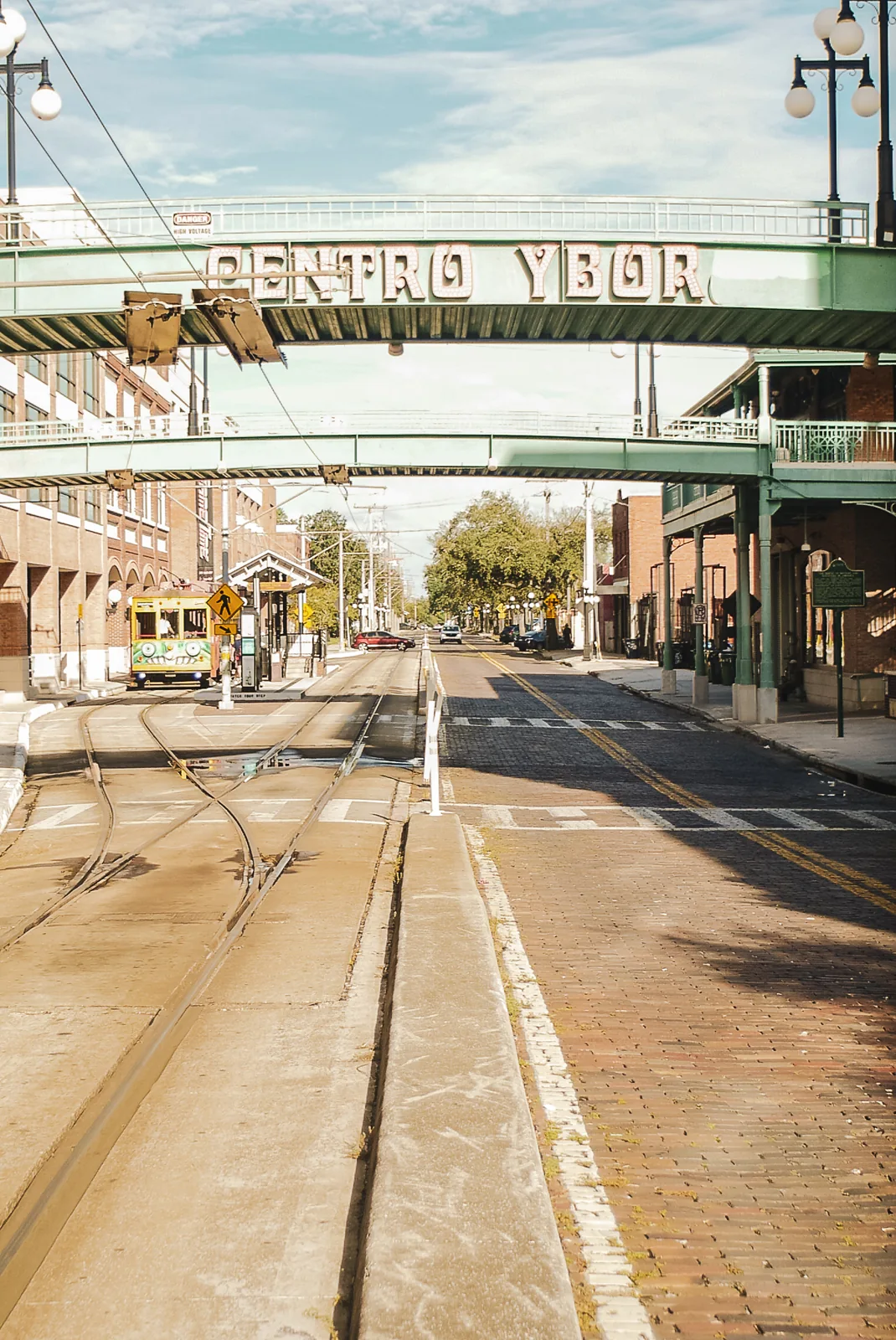 Sunlit streetcar tracks beneath the Centro Ybor pedestrian bridge